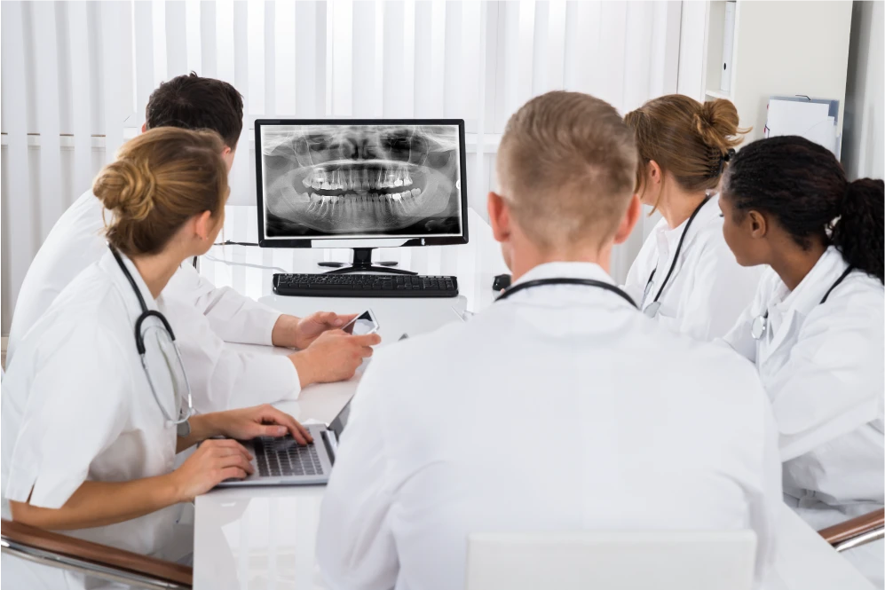 Dentists reviewing dental X-ray and treatment plan on a computer screen